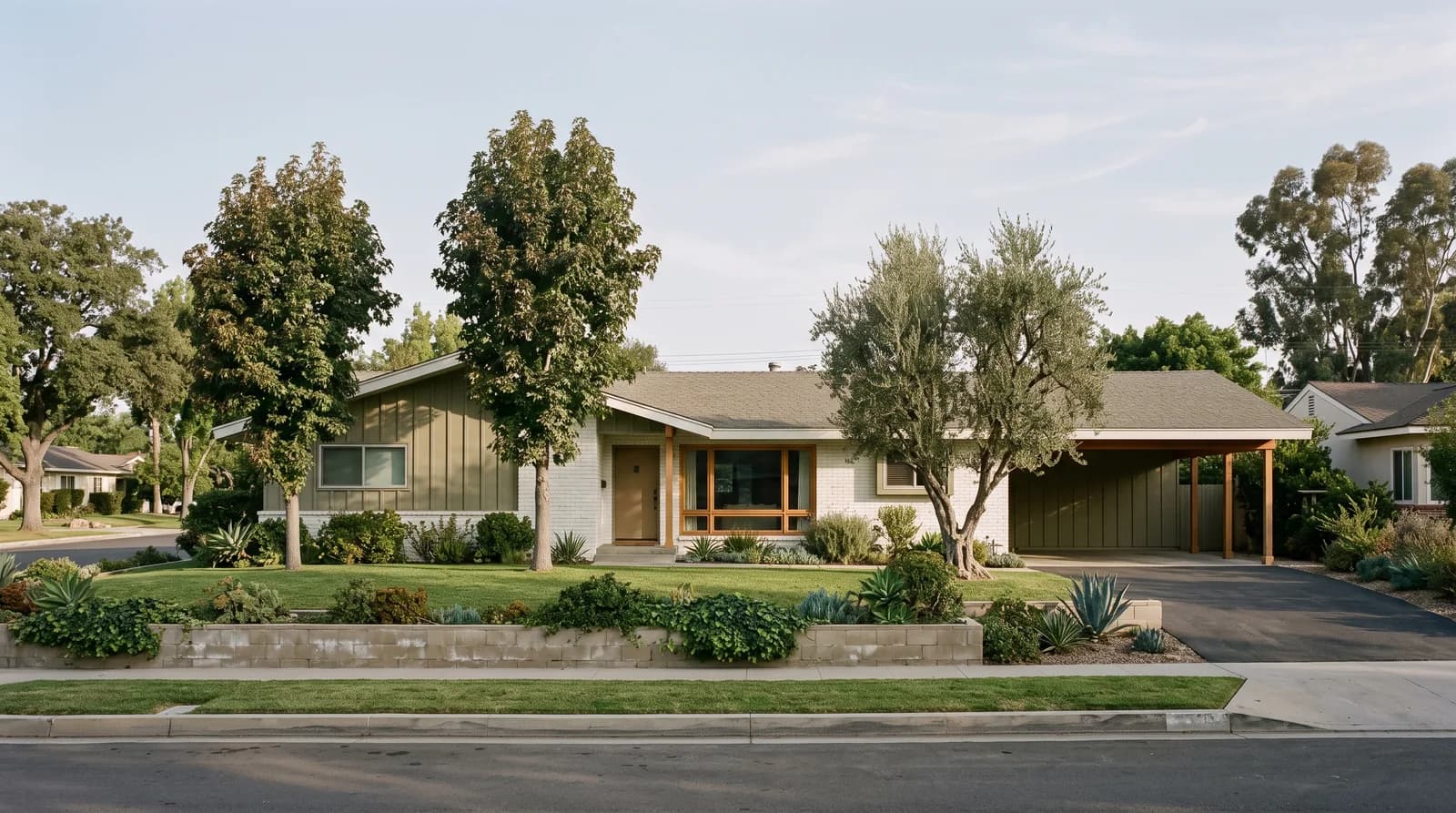A single-story postwar California ranch house on a deep lot, seen from the street