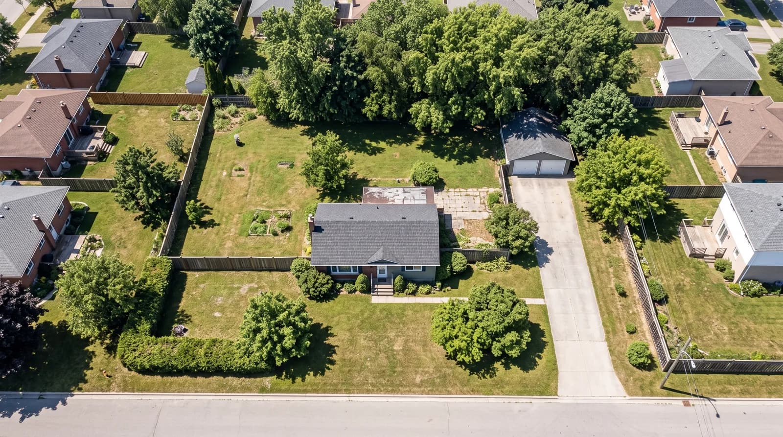 Aerial view of a single suburban residential lot with a modest older house set back from the street